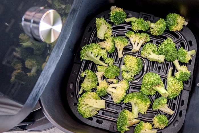 raw broccoli in black air fryer tray