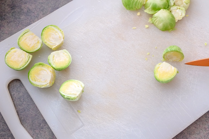 brussels sprouts cut in half on white plastic cutting board