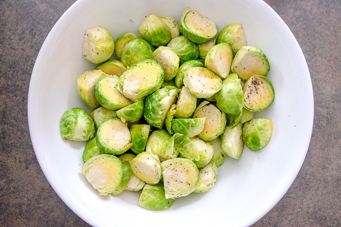 brussels sprouts in white bowl with oil and spices