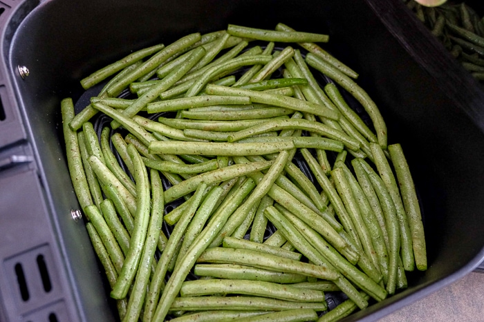 raw green beans in black air fryer tray