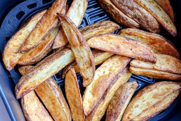cooked potato wedges in black air fryer tray