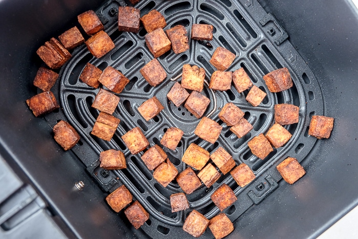 cooked tofu bits in black air fryer tray