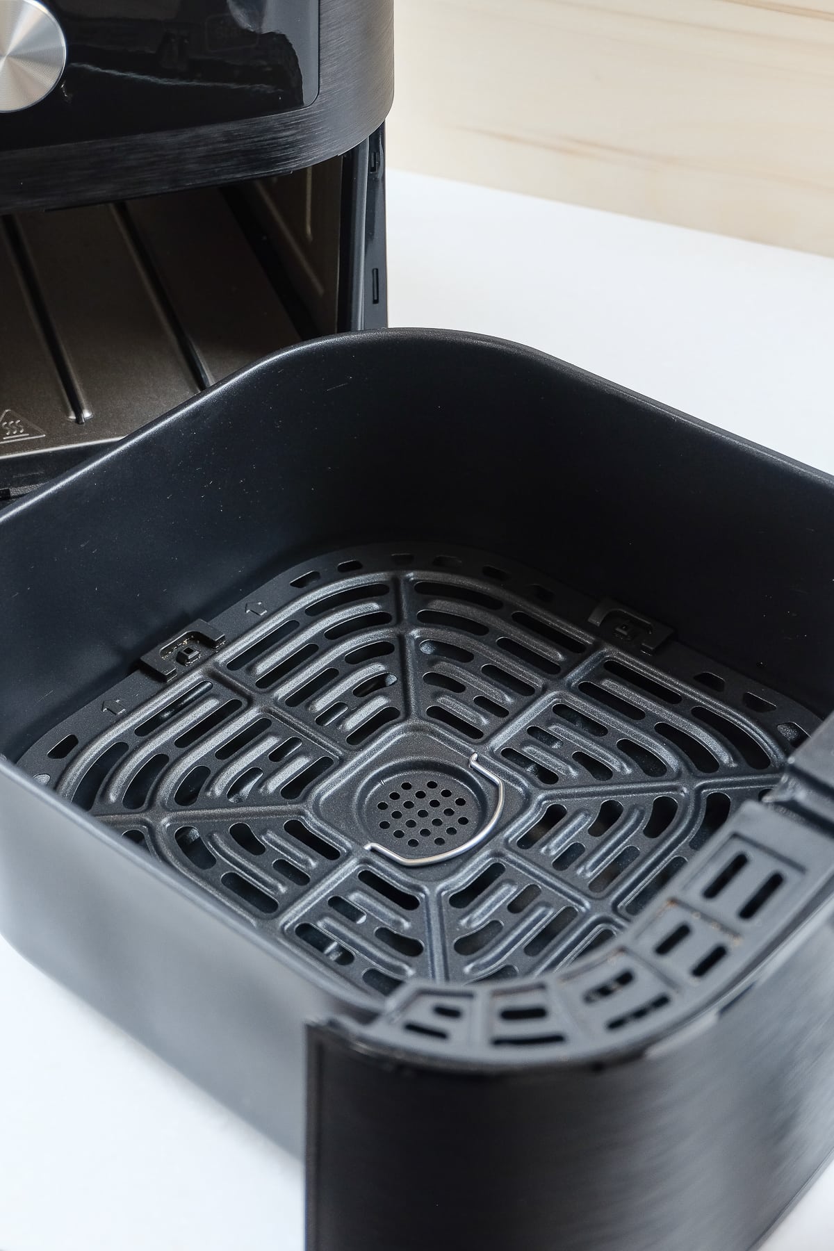black air fryer with open tray on white counter