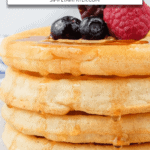 cooked waffles stacked with berries on top and maple syrup dripping down the sides plus text overlay saying "air fryer frozen waffles"