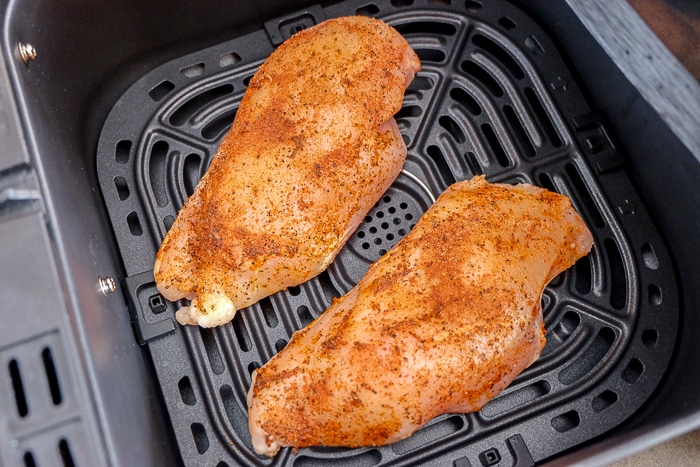 raw chicken breast in black metallic air fryer tray