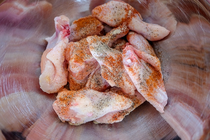 raw chicken wings in silver bowl with spices