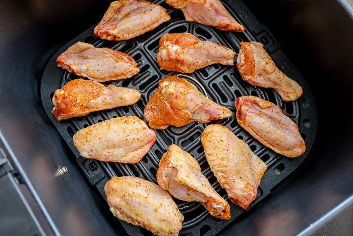 raw chicken wings on black air fryer tray