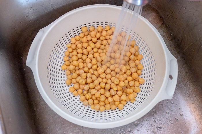 rinsing chickpeas in sink in white strainer.