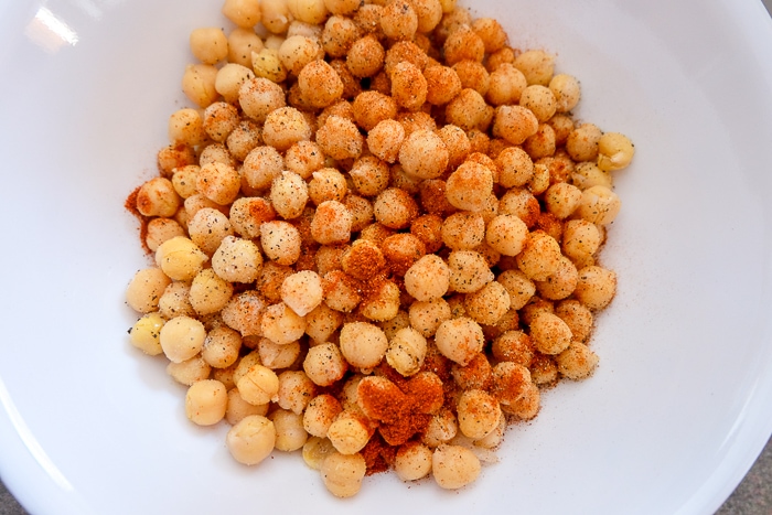 chickpeas in white bowl with red spices on top.