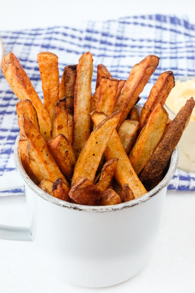 homemade french fries in cup with mayo behind
