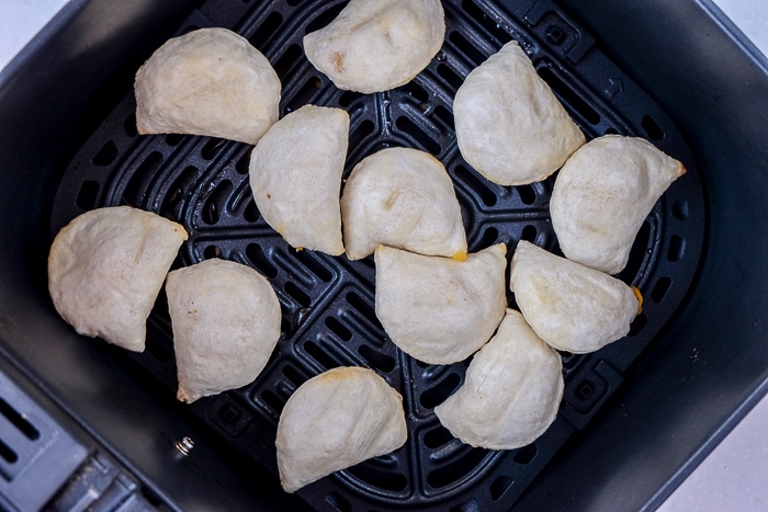 cooked pierogies laying in black air fryer tray