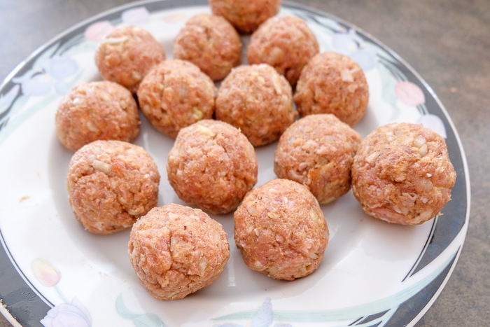 rolled meatballs on white plate on counter top.