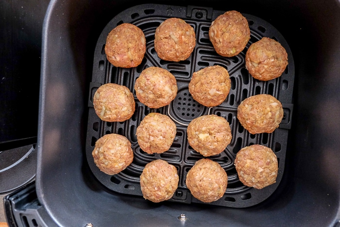 raw meatballs in black air fryer basket.