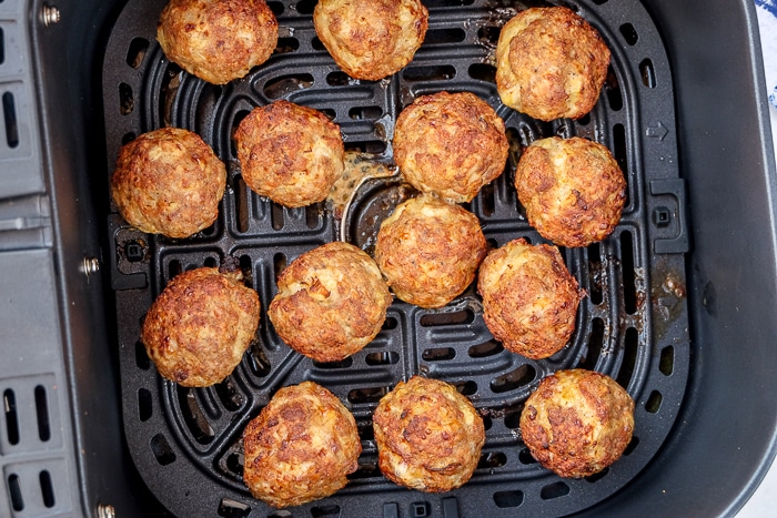 cooked meatballs in black air fryer basket.