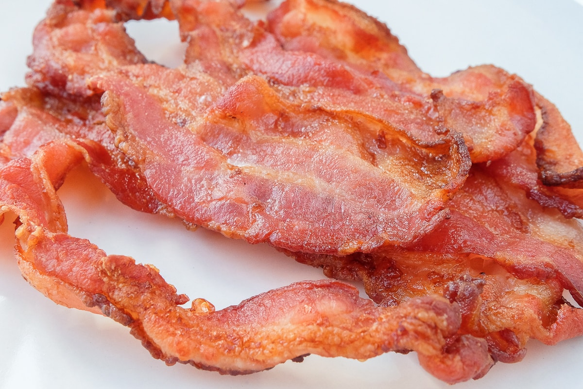 crispy bacon laying on white plate