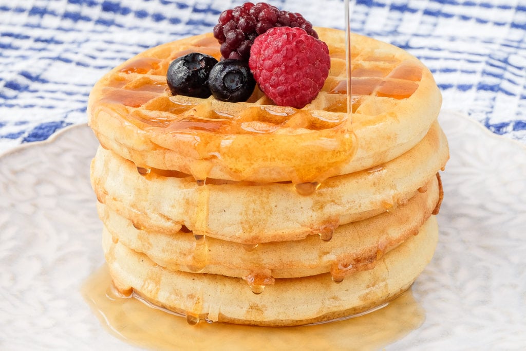 stack of waffles with syrup and berries on top