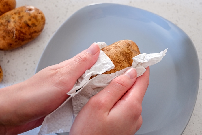 raw potato patted dry in paper towel with plate below
