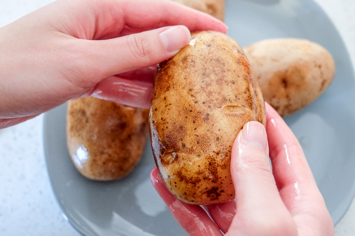 russet potato covered in oil held in hands