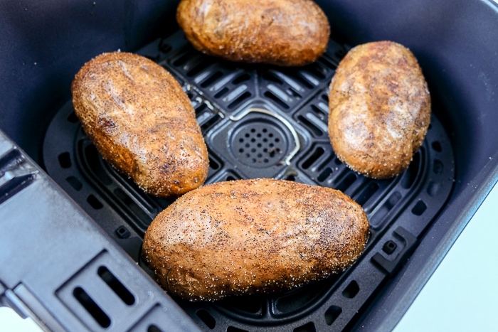 cooked and salted baked potatoes in air fryer tray