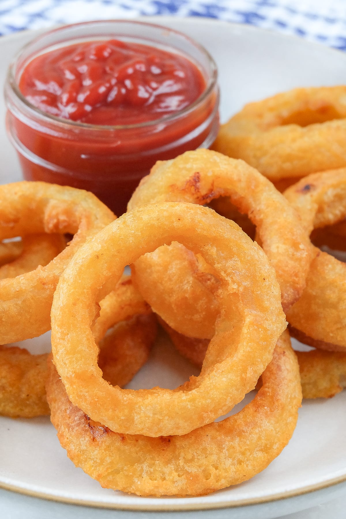 cooked onion rings in bowl with dish of ketchup behind