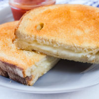 grilled cheese on plate with ketchup behind