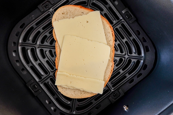 slices of cheese on piece of bread sitting in air fryer tray