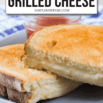 two halves of grilled cheese sandwich on plate with ketchup in glass jar in background and text overlay saying "air fryer grilled cheese"