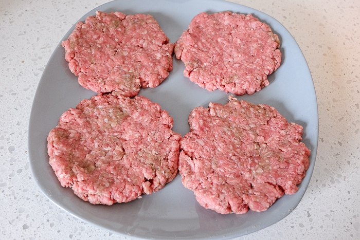 raw hamburger patties on gray plate on counter