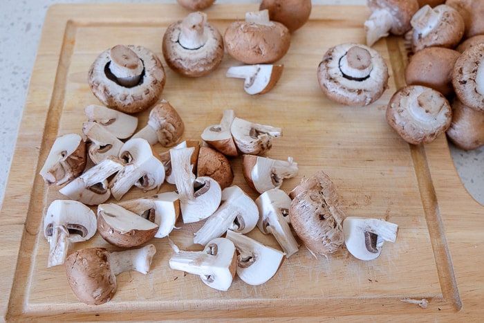 mushrooms cut up on wooden cutting board on counter