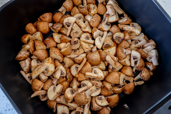 raw mushrooms in black air fryer tray