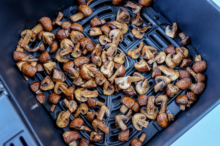 cooked mushrooms in black air fryer tray