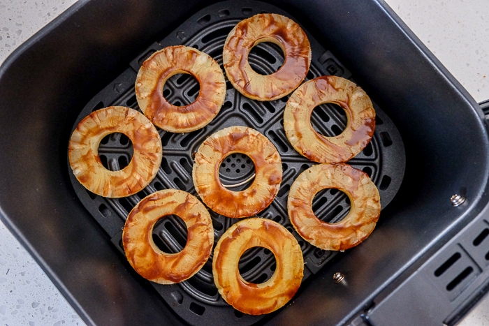 rings of pineapple with cinnamon mixture in black air fryer tray