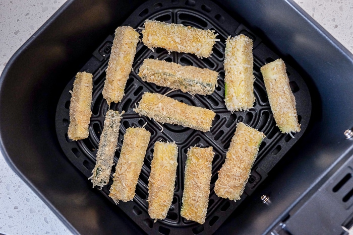 breaded zucchini fries in black air fryer tray