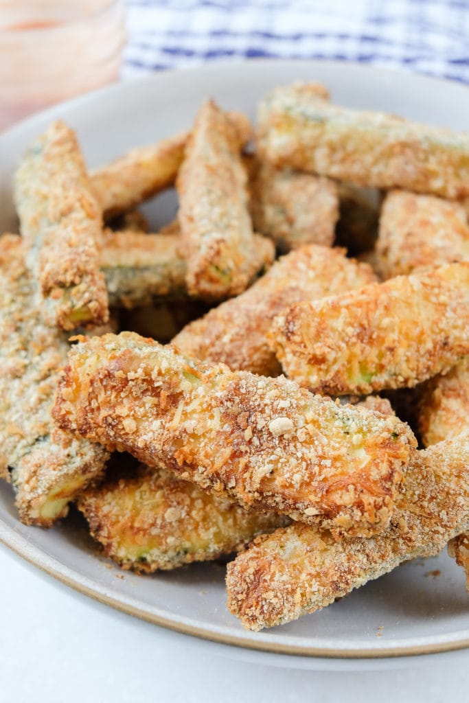 breaded zucchini fries in bowl with sauce behind