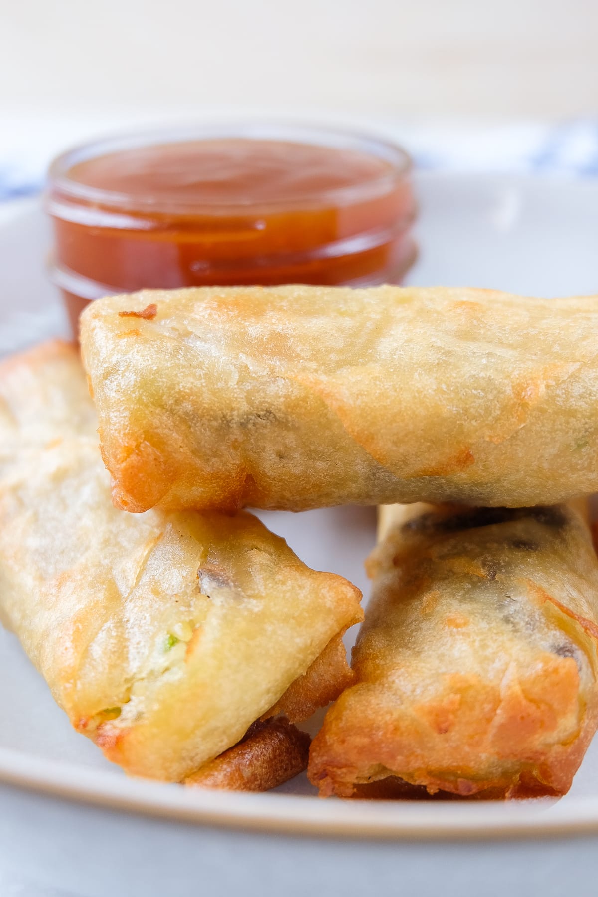 crispy spring rolls in bowl with dipping sauce behind