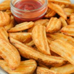 cooked potato wedges in bowl with ketchup in dish