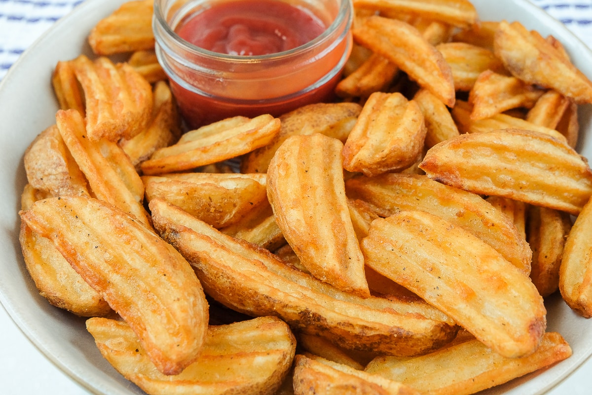 cooked potato wedges in bowl with ketchup in dish