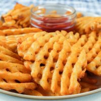 crispy waffle fries in bowl with ketchup behind