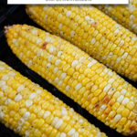 cooked corn on the cob in black air fryer with text overlay 