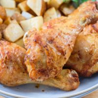 crispy chicken legs in bowl with potatoes