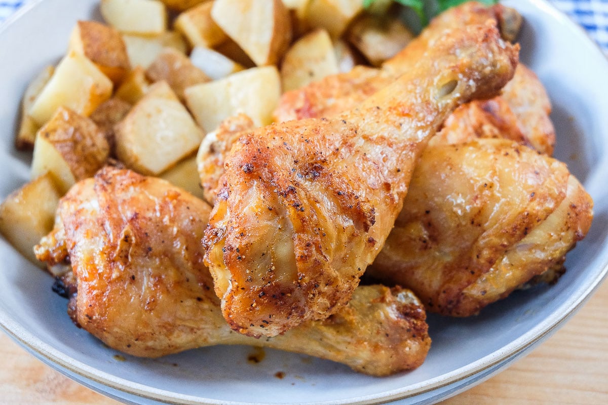 crispy chicken drumsticks in bowl with potatoes