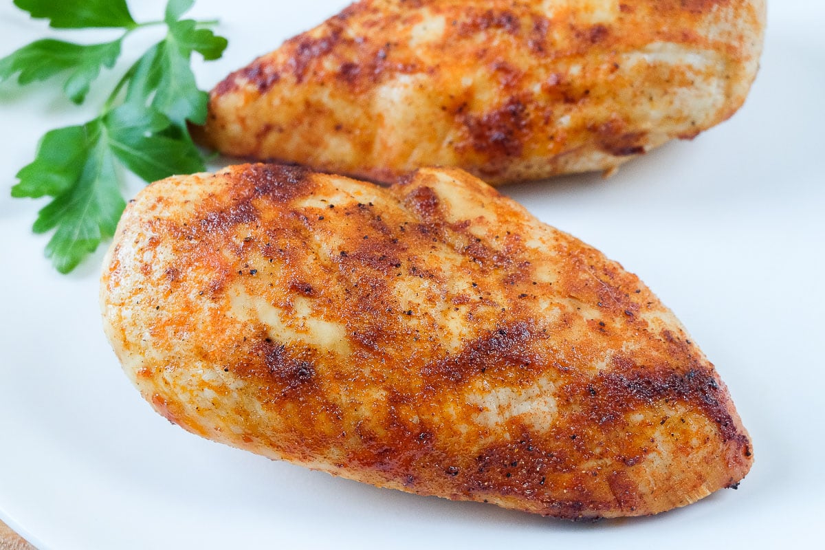cooked chicken breast with red spices on white place with parsley