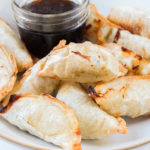 cooked dumplings in bowl with dipping sauce behind