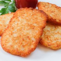 crispy hashbrowns on plate with ketchup behind
