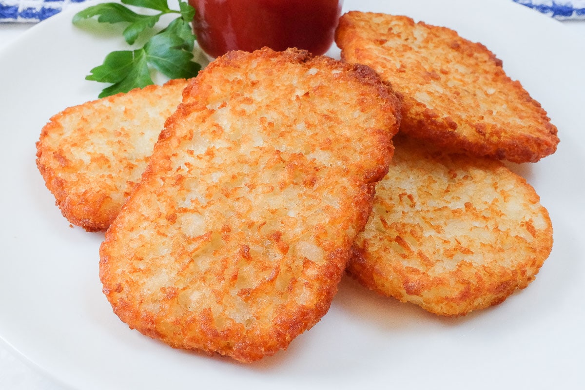 crispy hashbrowns on plate with ketchup behind