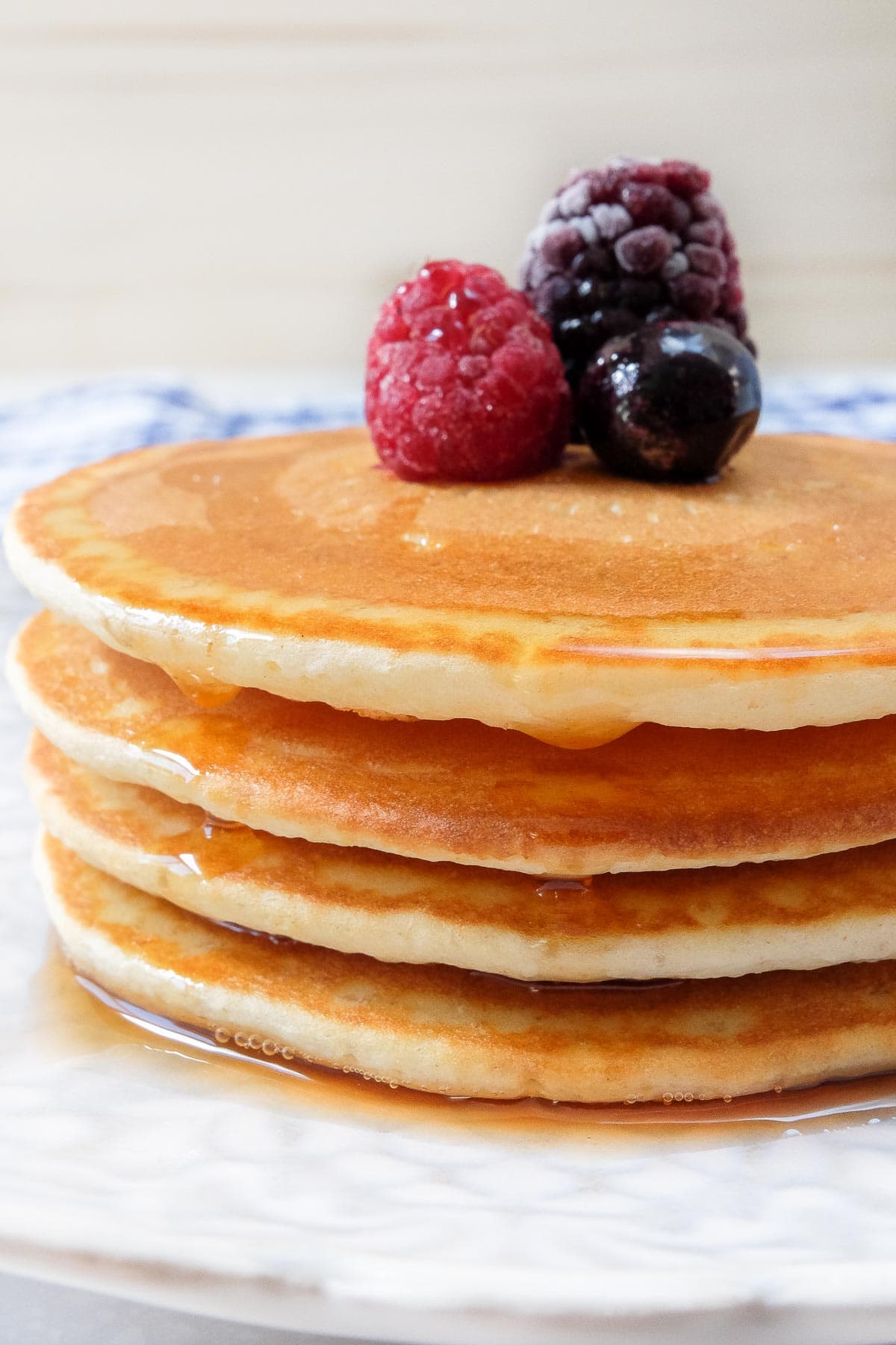 stack of pancakes with berries on top and syrup on plate