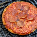 small cooked pizza in black air fryer tray