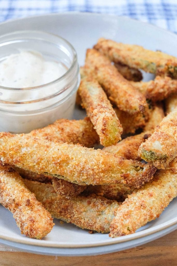 breaded pickles in bowl with ranch dipping sauce behind