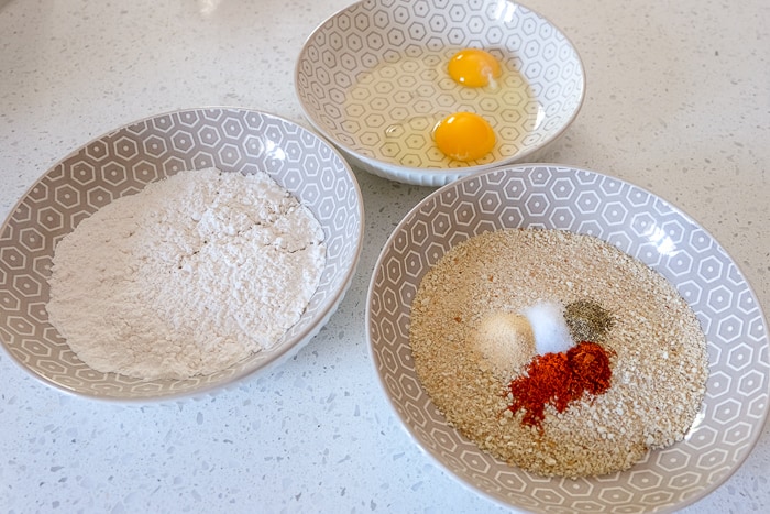 three bowls of breadcrumbs egg and flour on counter top
