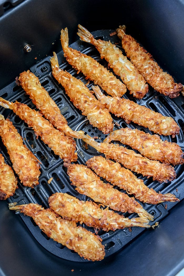cooked crispy coconut shrimp in black air fryer tray